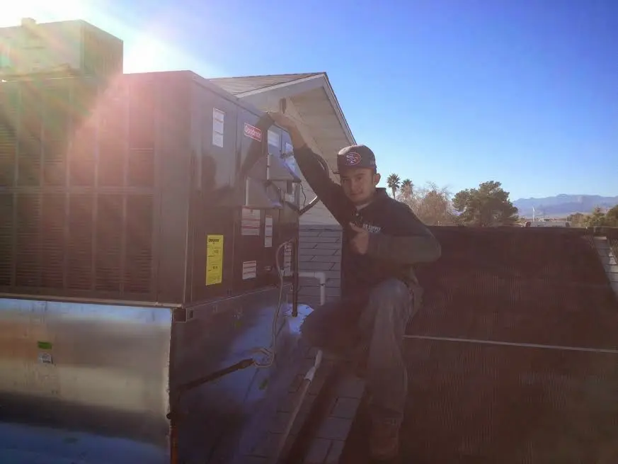HVAC technician performing AC Tune-Up on a rooftop unit in Reminderville